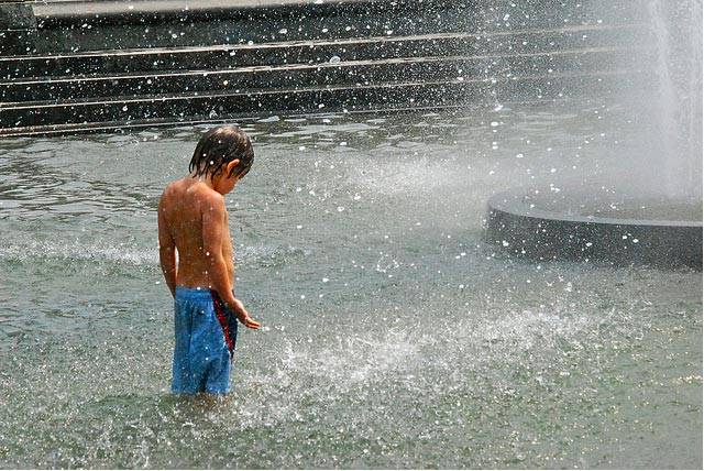 A boy cools off in the fountain at Washington Square Park